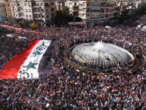 Pro-Syrian regime protesters, carry a giant Syrian flag during a demonstration against the Arab League decision to suspend Syria, in Damascus, Syria, on Sunday Nov. 13, 2011. Tens of thousands of pro-regime demonstrators gathered in a Damascus square Sunday to protest the Arab League's vote to suspend Syria over its bloody crackdown on the country's eight-month-old uprising. Saturday's Arab League decision was a sharp rebuke to a regime that prides itself as a bastion of Arab nationalism, but it was unlikely to immediately end a wave of violence that the U.N. estimates has killed more than 3,500 people since mid-March. (AP Photo/Muzaffar Salman)