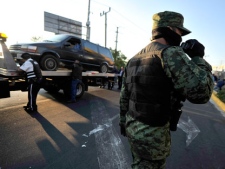 A soldier patrols as a vehicle that was discovered carrying bodies inside is taken away in Guadalajara, Mexico, Thursday Nov. 24, 2011. At least 20 bodies were discovered early Thursday in three vehicles abandoned in the heart of Guadalajara, Mexico's second-largest city and the site of the recent Pan American Games, according to an official with the prosecutor's office in the state of Jalisco. (AP Photo/Victor Fernandez)