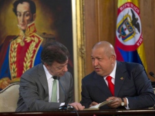 Venezuela's President Hugo Chavez, right, and Colombia's President Juan Manuel Santos check documents during a signing agreements ceremony at Miraflores presidential palace in Caracas, Venezuela, Monday Nov. 28, 2011. Colombian authorities say one of the country's most-wanted drug traffickers has been captured in Venezuela. The U.S. government had offered a $5 million reward for information leading to the arrest of Maximiliano Bonilla Orozco, who is best known by his alias "Valenciano." In background, a painting depicting Venezuela's independence hero Simon Bolivar. (AP Photo/Ariana Cubillos)