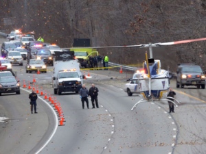 A State Police helicopter lands on the southbound lanes of route 287 in Harding Township, N.J., where a small plane headed for Georgia crashed, raining debris down on the highway and local streets Tuesday, Dec. 20, 2011. The plane spiraled out of control and lost a section of the aircraft before hitting the wooded median strip, skidding into the roadway and exploding. All five people aboard were killed but no one on the ground was injured. (AP Photo/Joe Epstein)