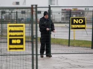 A guard locks a security fence surrounding the locomotive-maker Electro-Motive facility in London, Ont., on Sunday, Jan. 1, 2012 in anticipation of a work stoppage. (THE CANADIAN PRESS/Dave Chidley)