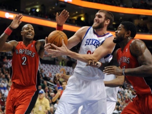 Philadelphia 76ers' Spencer Hawes (00) pulls in a rebound over Toronto Raptors' James Johnson (2) and Amir Johnson (15) in the first half of an NBA basketball game on Saturday, Jan. 7, 2012, in Philadelphia. (AP Photo/Michael Perez)