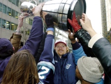 Toronto Argonauts Mike O'Shea, centre, takes the Grey Cup to the fans on the street during the Grey Cup Parade in Toronto Tuesday Nov. 23, 2004. (CP PHOTO/Aaron Harris)