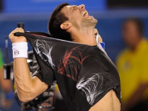 Serbia's Novak Djokovic rips his shirt off as he celebrates his win over Spain's Rafael Nadal in the men's singles final at the Australian Open tennis championship, in Melbourne, Australia, early Monday, Jan. 30, 2012. (AP Photo/Andrew Brownbill)