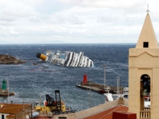 The grounded cruise ship Costa Concordia lies on its side off the Tuscan island of Giglio, Italy, Wednesday, Feb. 1, 2012. Bad weather conditions forced the temporary suspension of the recovery operation of the capsized cruise ship Costa Concordia.The ship contains about 500,000 gallons (2,400 tons) of heavy fuel and other pollutants, and fears are growing that those pollutants could spill out, damaging a pristine environment that is home to dolphins, whales and other marine life. (AP Photo/Pier Paolo Cito)