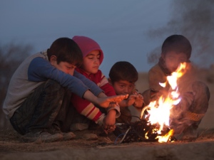 In this Dec. 21, 2011, file photo, children who survived an earthquake warm themselves up next to their tents in Van, Turkey. The harshest winter in decades has added to the woes of more than 140,000 quake survivors who are braving record low temperatures and heavy snowfall in tents or temporary homes. (AP Photo/Kerem Yucel, File)