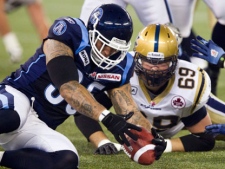 Toronto Argonauts linebacker Kevin Eiben (left) scoops up a fumble in front of Winnipeg Blue Bombers offensive lineman Glenn January (69) during first half CFL action in Toronto on Saturday July 23, 2011. THE CANADIAN PRESS/FRANK GUNN
