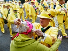 A member of Pete Fountain's Half Fast Marching Club hands out beads as the club begins its traditional parade through the streets of New Orleans on Tuesday, Feb. 21, 2012, on the last day of the city's Mardi Gras celebration. (AP Photo/Bill Haber)