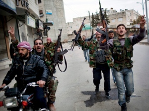 In this Sunday, March 11, 2012, file photo, Free Syrian Army fighters celebrate after hearing that their comrades destroyed a Syrian Army tank in Idlib, Syria. (AP Photo/Rodrigo Abd, File)