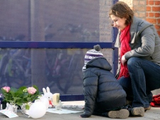 A mother and child light a candle at the gate of the Sint Lambertus school in Heverlee, Belgium, Thursday, March 15, 2012, after pupils of the school were involved in a fatal bus crash in Switzerland. (AP Photo/Yves Logghe)