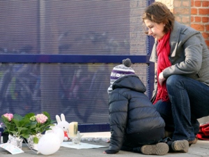 A mother and child light a candle at the gate of the Sint Lambertus school in Heverlee, Belgium, Thursday, March 15, 2012, after pupils of the school were involved in a fatal bus crash in Switzerland. (AP Photo/Yves Logghe)