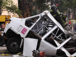 A firefighter leans against the roof of a damaged mini-bus while standing on a beam that fell from a bridge onto the bus during an earthquake in Mexico City on Tuesday, March 20, 2012. (AP Photo/Alexandre Meneghini)