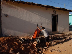 A young resident dumps a wheelbarrow of collected debris onto a pile of rubble, caused by Tuesday's magnitude-7.4 quake, as town residents clean up the damage in San Juan Cacahuatepec, in the Mexican state of Oaxaca, near the border with Guerrero, early on Wednesday, March 21, 2012. (AP Photo/Luis Alberto Cruz Hernandez)