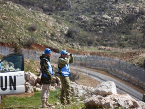 UN officers, one using binoculars, look towards Syria as they stand along the border between Majdal Shams in the Golan Heights and Syria, as security is tightened ahead of Land Day on Friday, March 30, 2012. March 30 is traditionally marked by Israeli Arabs as "Land Day," a time of protests against the confiscation of Arab-owned lands by Israel. In recent years, Palestinians have joined in. (AP Photo/Ariel Schalit)