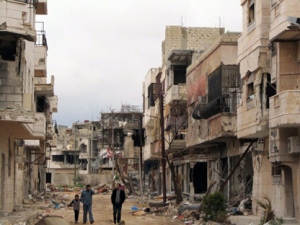 In this Sunday, April 15, 2012, photo, Syrians walk between destroyed buildings in the Inshaat neighborhood of Homs, Syria. (AP Photo)