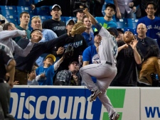 Seattle Mariners left fielder Chone Figgins leaps near fans to catch a foul ball by Toronto Blue Jays Jose Bautista during fifth inning AL action in Toronto on Sunday, April 20, 2012. THE CANADIAN PRESS/Frank Gunn