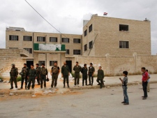 In this picture taken during a UN observer-organized tour, Syrian boys, right, look at Syrian army soldiers, left, as they stand outside a school building used as a temporary military base in Hama city, central Syria, on Thursday, May 3, 2012. (AP Photo/Muzaffar Salman)