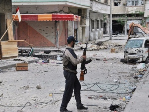 A Syrian rebel walks past destroyed shops at al-Bayada neighborhood in Homs, Syria, Thursday, May 10, 2012. (AP Photo)