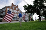 David Clark places flags for the Fourth of July celebrations along the Town Green, Friday, July 3, 2015, in Middlebury, Vt. (AP / Mel Evans)