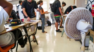 With only open windows and fans to cool the room down, students enter their non-air conditioned classroom at Campbell High School, Ewa, Hawaii on Aug. 3, 2015. (AP / Marco Garcia)