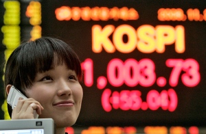 An employee uses her mobile phone in front of an electronic stock board at the Korea Stock Exchange Market in Seoul, South Korea, Friday, Nov. 21, 2008. (AP / Ahn Young-joon)