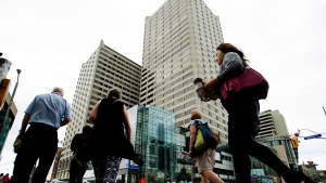 Pedestrians walk by an office tower in Toronto on Friday, Aug. 21, 2015. (Nathan Denette / THE CANADIAN PRESS)