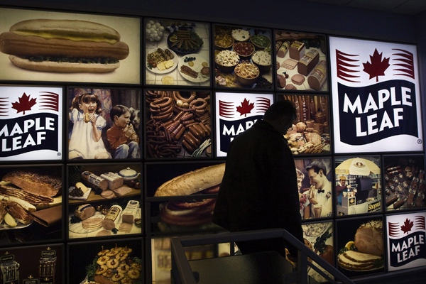 A Maple Leaf Foods employee walks past a Maple Leaf sign at the company's meat facility in Toronto, on Monday, Dec. 15, 2008. (Nathan Denette / THE CANADIAN PRESS)