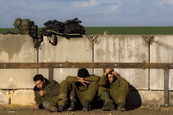 Israeli soldiers rest next to a barrier wall after leaving the Gaza Strip into Israel Sunday, Jan. 18, 2009. (AP / Sebastian Scheiner)