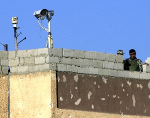 An Egyptian border police officer stands next to recently installed security cameras on a building at the Egyptian side of Rafah, at the border between Egypt and Rafah, in the southern of Gaza Strip, Sunday, Feb. 1, 2009. (AP / Eyad Baba) 