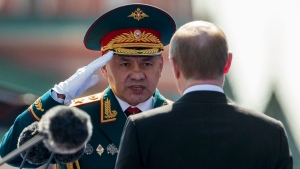 In this photo taken on Monday, May 9, 2016, Russian Defense Minister Sergei Shoigu, left, salutes to Russian President Vladimir Putin, back to a camera, prior the Victory Day Parade on the Red Square, which commemorates the 1945 defeat of Nazi Germany in Moscow, Russia. Shoigu says the airstrikes were suspended starting from 10 a.m. on Tuesday, Oct. 18 and the suspension is intended to prepare for the opening of humanitarian corridors for the rebels to leave the besieged city of Aleppo. (AP Photo/Alexander Zemlianichenko)