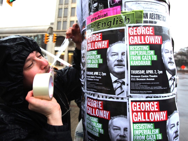 Dylan Penner, with Ottawa Peace Assembly, tapes a poster of British MP George Galloway on a downtown Ottawa street post on Thursday March 26, 2009. (Fred Chartrand / THE CANADIAN PRESS)