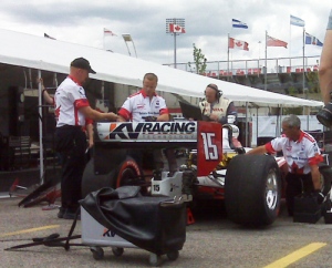 Officals examine the car driven by Paul Tracy after it spins out during the Honda Indy auto race on Sunday, July 12, 2009. 