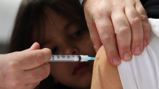 Four-year-old Rowan Watchmaker looks on as her mother is injected with the H1N1 flu vaccine at a clinic in Ottawa, Monday, Oct. 26, 2009. (Fred Chartrand / THE CANADIAN PRESS)