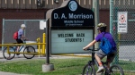 Kids ride their bikes past the sign for D.A. Morrison school in Toronto on June 2, 2021. THE CANADIAN PRESS/Frank Gunn 