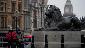 People wearing face masks to curb the spread of coronavirus walk through Trafalgar Square backdropped by the Elizabeth Tower of the Houses of Parliament, known as Big Ben, in London, Tuesday, Jan. 11, 2022. (AP Photo/Matt Dunham) 