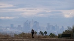 A woman walks at Kenneth Hahn State Recreation Area as storm clouds move over the Los Angeles skyline on Sept. 10, 2022. (AP Photo/Ringo H.W. Chiu)