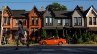 A person walks by a row of houses in Toronto on Tuesday July 12, 2022. THE CANADIAN PRESS/Cole Burston 