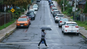 A person carries an umbrella during a downpour of rain in Toronto on Tuesday, Sept. 27, 2022. THE CANADIAN PRESS/Alex Lupul