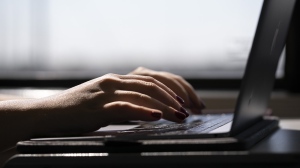 A woman types on a laptop