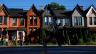 A person walks by a row of houses in Toronto on Tuesday July 12, 2022. THE CANADIAN PRESS/Cole Burston 