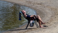 A man relaxes on the banks of the Ottawa River in Ottawa on Tuesday, July 4, 2023 amid a heat warning for the nation's capital and Ontario and Quebec. (THE CANADIAN PRESS/Sean Kilpatrick)