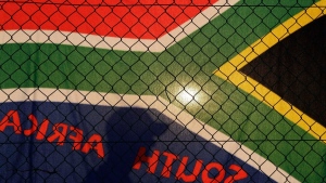 A tourist passes a South African flag hanging on a fence along a busy sidewalk, July 4, 2010, in Cape Town, South Africa. (AP Photo/Julie Jacobson)