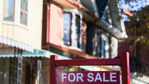A real estate sign is displayed in front of a house. (Evan Buhler / The Canadian Press)