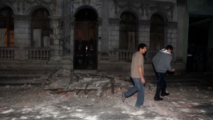 Residents walk by debris in Santiago de Chile after an 8.8-magnitude earthquake struck central Chile early Saturday Feb. 27, 2010. (AP / Aliosha Marquez)