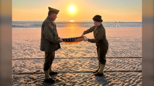 Christophe Receveur and his daughter Julie of France unfold an American flag to mark D-Day on Thursday, June 6, 2024 on Utah Beach, Normandy. (John Leicester / AP Photo)