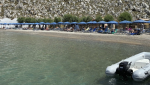 People sit on the beach of Agios Nikolaos from where British doctor and television presenter Michael Mosley, is believed to have set out, on the southeastern Aegean Sea island of Symi, Greece, Friday, June 7, 2024. (AP Photo/Antonis Mystiloglou)
