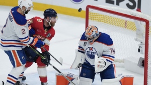 Edmonton Oilers goaltender Stuart Skinner (74) makes a save as Florida Panthers' Sam Bennett (9) eyes the loose puck next to Oilers' Evan Bouchard (2) during second period action in Game 1 of the NHL Stanley Cup final in Sunrise, Fla. on June 8, 2024. THE CANADIAN PRESS/Nathan Denette