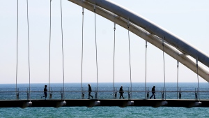 People enjoy the above seasonal warm weather as they cross the Humber River on a bridge in Toronto on Monday, March 4, 2024. THE CANADIAN PRESS/Nathan Denette