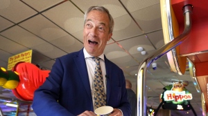 Britain's Nigel Farage, Reform U.K. party leader plays on a game in an amusement arcade holds out some coins whilst spending time with supporters in Clacton-On-Sea, Essex, England Friday, June 21, 2024. (AP Photo/Kirsty Wigglesworth)