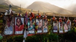 Photos of victims are displayed under white crosses at a memorial for the August 2023 wildfire victims, above the Lahaina Bypass highway, Dec. 6, 2023, in Lahaina, Hawaii. (AP Photo/Lindsey Wasson, File)
